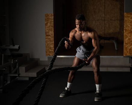 Attractive african american man with naked torso doing endurance exercises with trope