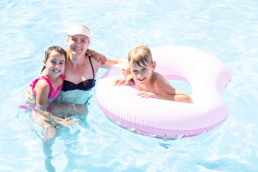 Young mother with children sitting on the edge of the pool.