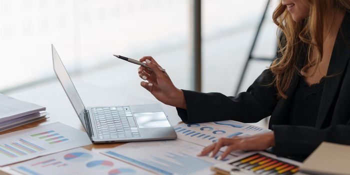 Asian Business woman working to analyze technical price graph and indicator with business team talking by cell phone. account or saving money or insurance concept