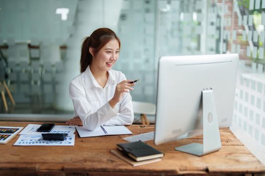 Data analysis, roadmap, marketing, accounting, auditing. Portrait of Asian businesswoman using computer in video conferencing, presenting marketing plan using statistical data sheet at work