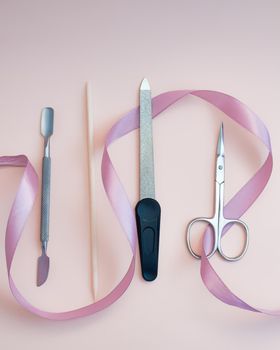 A set of cosmetic tools for manicure and pedicure on a pink background. Gel polishes, nail files, manicure scissors. photo