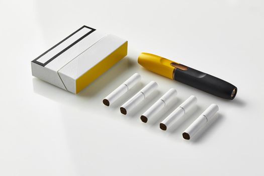 New generation black and yellow electronic cigarette, one pack and five heatsticks, isolated on white. New alternative technology. Heating tobacco system. Advertising area, workspace mock up. Close up