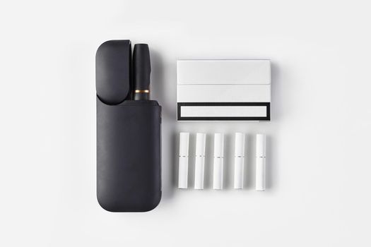 New generation black electronic cigarette in open battery, one pack, five heatsticks isolated on white. Heating tobacco system. Hybrid between analog and electronic. Close up, copy space, flat lay