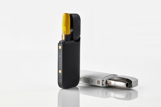 New generation black and yellow, white electronic cigarettes in open batteries isolated on white. Heating tobacco system. Tools used to help stop smoking. Advertising, close up, copy space, side view