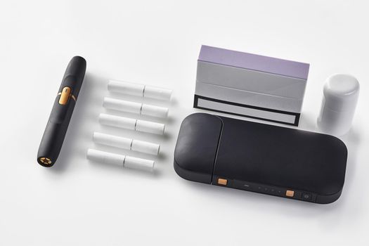 New generation black electronic cigarette, battery, cleaner, pack with purple side, five heatsticks isolated on white. Heating tobacco system. Tools used to help stop smoking. Close up, copy space