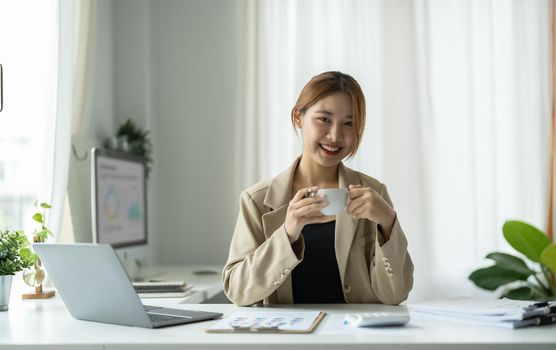 Portrait of young beautiful asian businesswoman looking at camera and smile, arms crossed in modern office workplace.