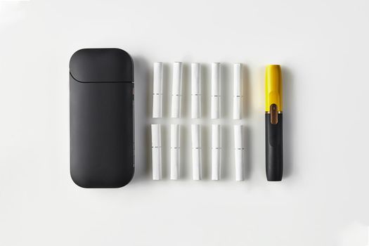New generation black and yellow electronic cigarette, battery and ten heatsticks isolated on white. New technology. Heating tobacco system. Template place for your text, image. Close up, flat lay