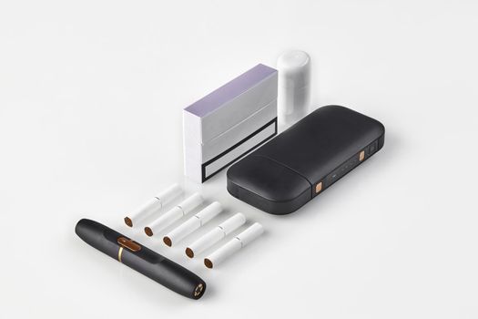 New generation black electronic cigarette, battery, cleaner, pack with purple side, five heatsticks isolated on white. Alternative technology. Heating tobacco system. Advertising, mock up. Close up