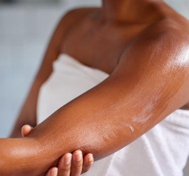Shot of a woman massaging lotion into her skin.