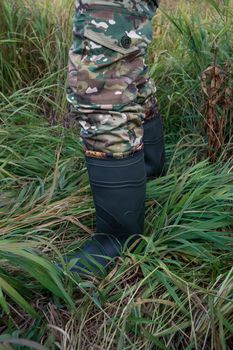 Hunter camouflage uniform closeup and rubber boots at outdoor