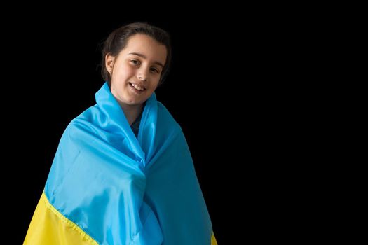 Little girl with Ukrainian flag on dark background.