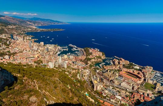 Aerial view of principality of Monaco at sunset, Monte-Carlo, luxury buildings, soccer stadium, view of city life from La Turbie mountain, a lot of mega yachts and boats, water horizon . High quality photo
