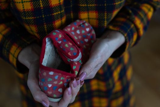Childrens slippers in mothers hands. War in Ukraine