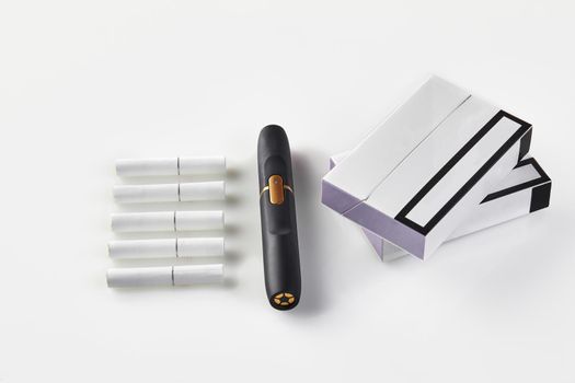 New generation black electronic cigarette, two packs with purple sides and five heatsticks isolated on white. Hi-tech heating tobacco system. Tools used to help stop smoking. Close up, copy space