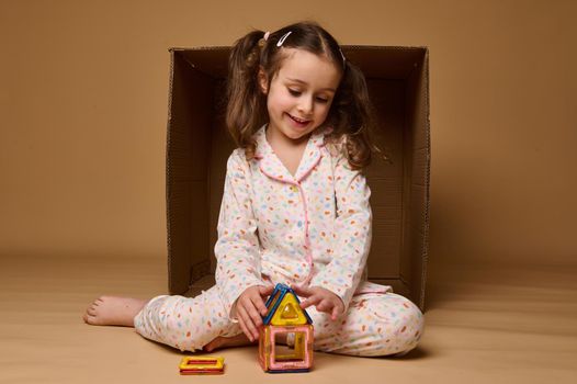 Beautiful European preschooler girl playing with lots of colorful plastic blocks constructor and building a cozy house. Fine motor skills development, kids entertainment and education concept