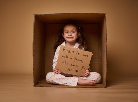 Conceptual studio shot for International Children's Day. Child with advertising banner calling for the observance and protection of the rights of children, the right to live in a happy loving family