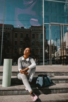Slim woman dressed in active wear resting in urban setting. People and sport concept