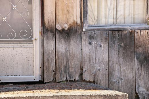 Close up of Weathered Wood Siding In State of Neglect and Disrepair Beginning Moldy Weathered and Rotting Around Front Step of Cottage or House. Copy Space Right