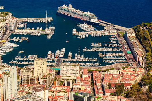 Aerial view of port Hercules of Monaco at sunset, Monte-Carlo, huge cruise ship is moored in marina, view of city life from La Turbie mountain, a lot of mega yachts and boats. High quality photo