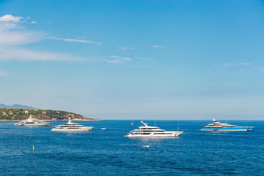The four huge mega yachts are moored in sea at sunny day, the chrome plated handrail, sun reflection on glossy board of the motor boat. High quality photo