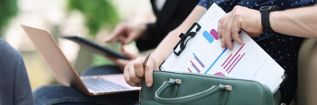 Man and woman with documents charts and laptop working at airport closeup. Business travel concept