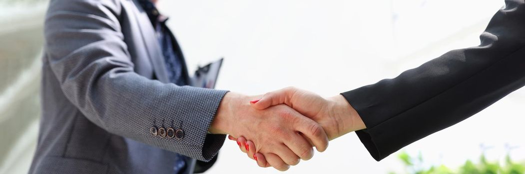 Business man and woman in suits shaking hands closeup. Business negotiations concept