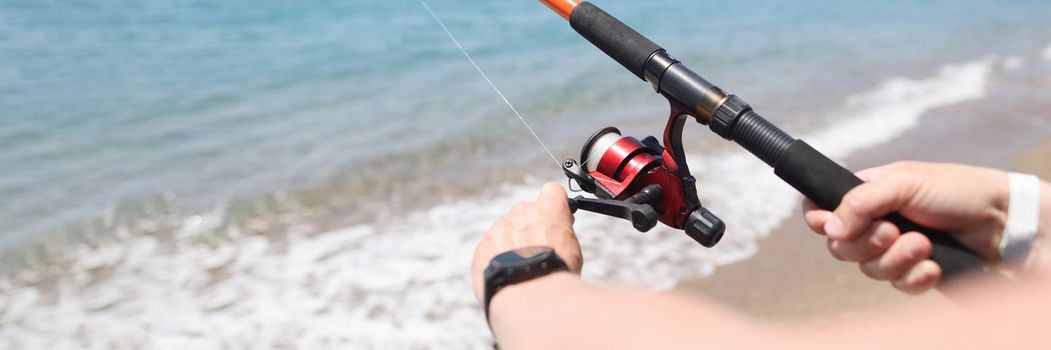 Man fishing with rod on seashore closeup. Men hobby fishing concept