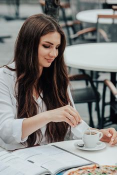 woman in a cafe pours milk cream into coffee cup. businesswoman lifestyle background