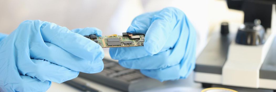 Scientists holding microchip in rubber gloves in laboratory closeup. Invention of new electronic technologies concept