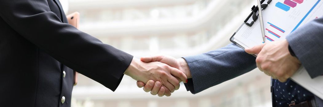 Business man and woman with documents shaking hands closeup. Business cooperation concept