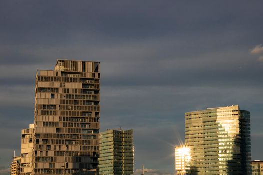 Some skyscrapers and the sun shining reflecting on a glass window on one of them in Barcelona