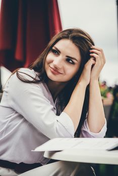 Smiling young dark-haired woman in a cafe. learning