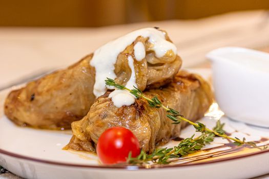 Stuffed cabbage rolls with meat on a plate with sour cream.