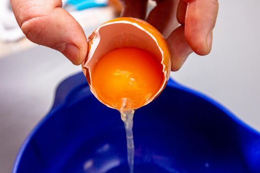The cook separates the egg yolk from the egg white in the shell.