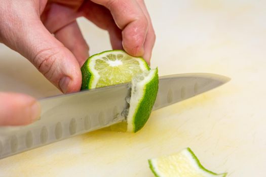 The chef cuts the skin from the lime with a knife on a white board in the restaurant