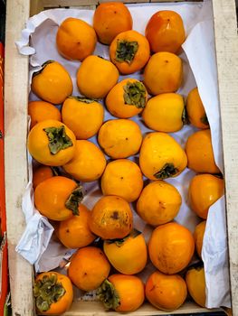 Fresh persimmon fruits are in a box in the store