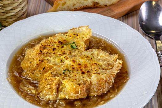 Classic French onion soup baked with cheese croutons sprinkled with fresh thyme, close up view.