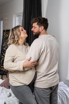 Happy family concept. Husband hug belly pregnant wife standing indoor living room near sofa Caucasian man and woman pregnancy and new life concept. Love and care