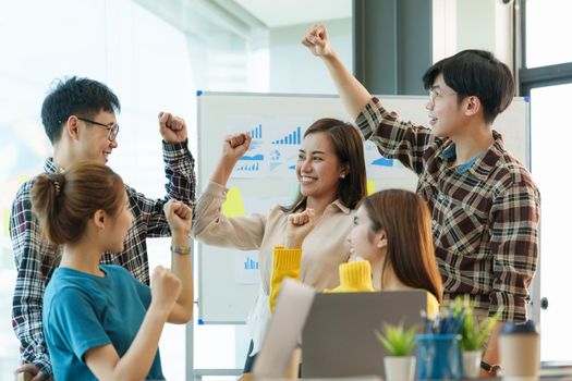 Asian business people give each other show hand of success symbol as they celebrate a successful team building project