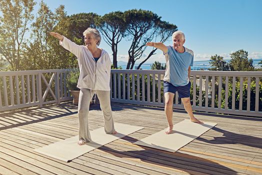 Shot of a senior couple doing yoga together on their patio outside.