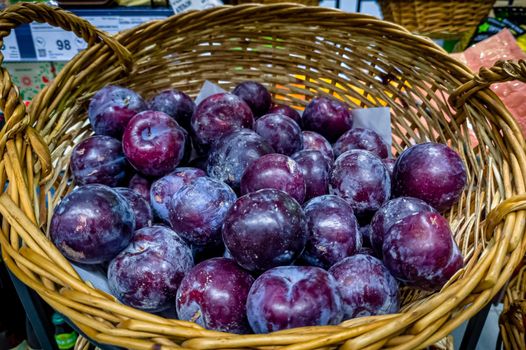 Blue plums are in a basket in the store.