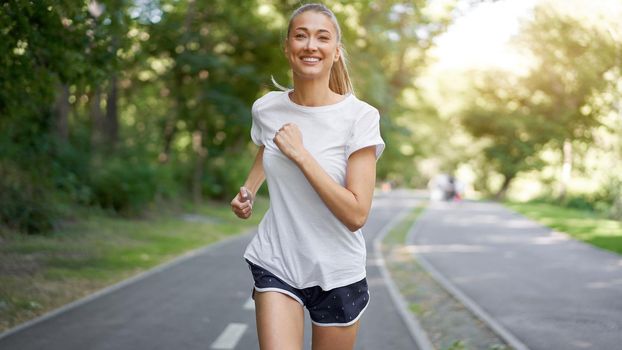 Woman running asphalt road summer park Active sporty caucasian female morning workout Healthy lifestyle concept. Athletic person sportswear exercises Dressed white t-shirt
