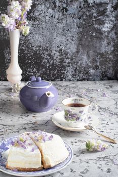 still life with black tea and cheese cake, spring bouquet of delicate lilac flowers. High quality photo