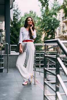 Beautiful young caucasian businesswoman in a white clothes with a laptop and notebook outdoor near business centre.