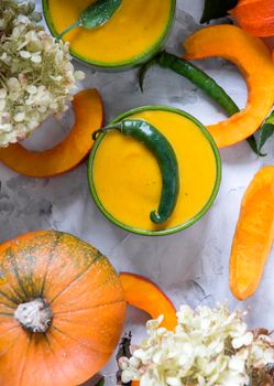 Pumpkin puree soup in green bowls on gray cement background, flat lay of colorful food, top view, autumn food. High quality photo