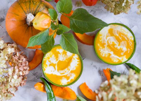 Pumpkin puree soup in green bowls on gray cement background, flat lay of colorful food, top view, autumn food. High quality photo