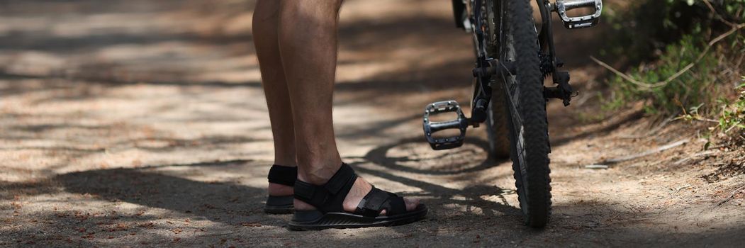 Man standing near mountain bike on path in forest closeup. Healthy lifestyle concept