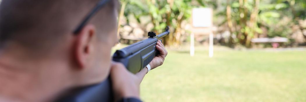 Man shooting gun at target on vacation closeup. Shooting training concept