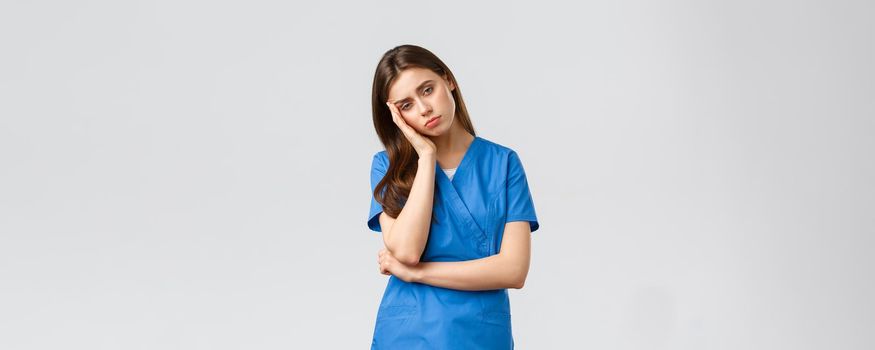 Healthcare workers, prevent virus, insurance and medicine concept. Exhausted and sleepy female nurse, doctor in scrubs, lean on palm look tired, feel fatigue from night shift at hospital.
