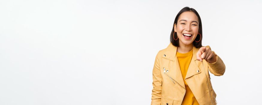 Congratulations, its you. Happy beautiful asian woman laughing, pointing finger at camera, choosing, inviting people, recruiting, standing over white background.
